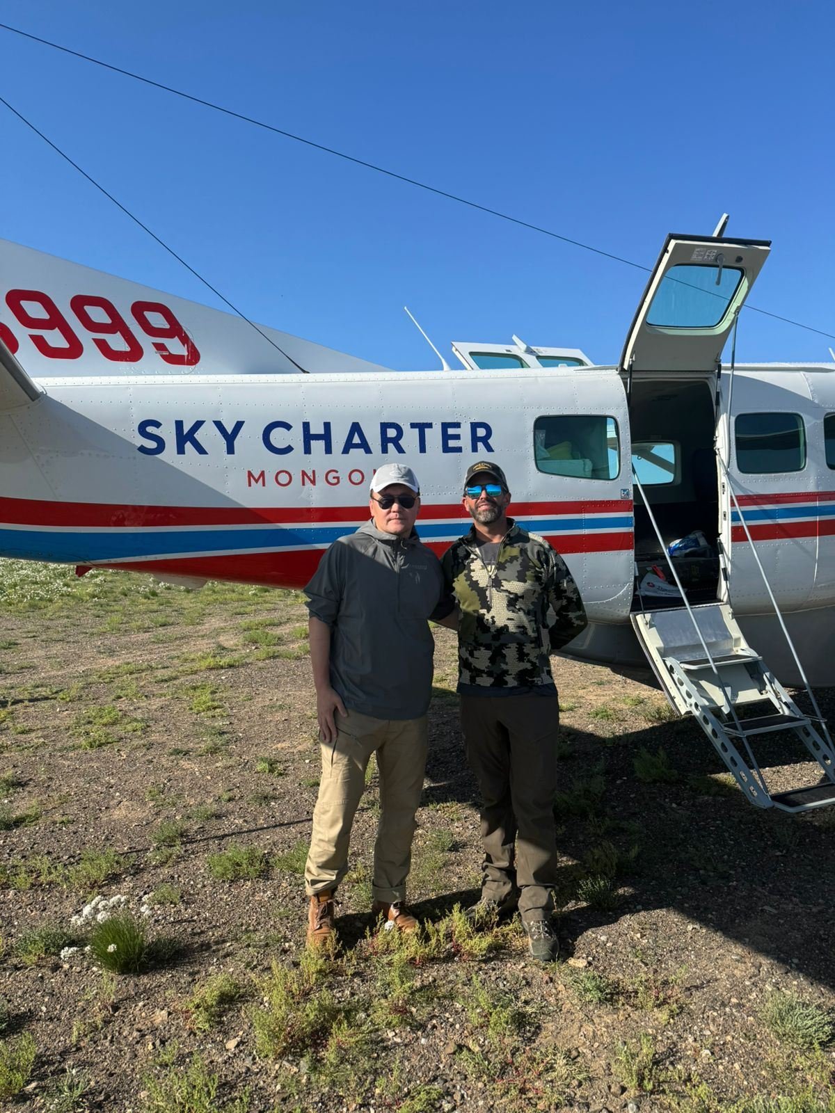 Hunters beside a charter aircraft on a remote Mongolian airstrip